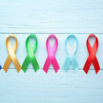Colorful awareness ribbons on light wooden background.