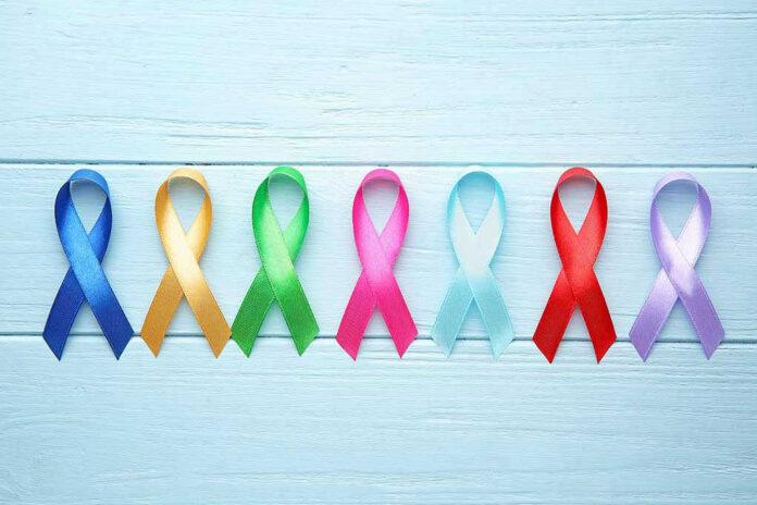Colorful awareness ribbons on light wooden background.