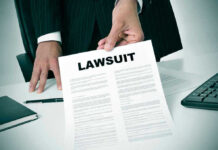 Person holding a document titled LAWSUIT in office.