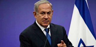 Man in suit giving speech in front of Israeli flag