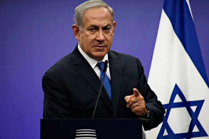 1042782061 Man in suit giving speech in front of Israeli flag