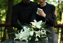 Mourners in black holding white flowers at funeral