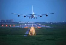 An airplane approaching the runway at night with landing lights illuminated