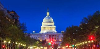 The U.S. Capitol building illuminated at night with city traffic in the foreground