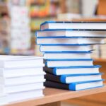 Epstein Survivor’s Memoir SPARKS Elite Panic A stack of neatly arranged books on a wooden table in a bookstore