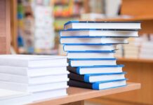 A stack of neatly arranged books on a wooden table in a bookstore