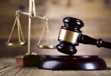 A wooden gavel and scales of justice on a wooden surface