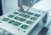 Body-Embedded Chip Fiasco – No Way Out! Robotic arm assembling electronic circuit boards in production.