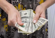 Hands holding a fan of hundred dollar bills