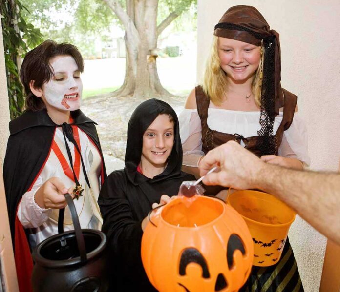 shutterstock_16961050.jpg Children in Halloween costumes collecting candy from a house