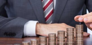 Businessman stacking coins in ascending order on a wooden table