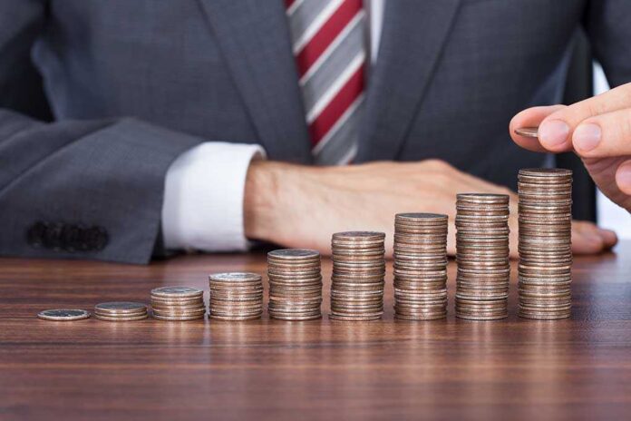 shutterstock_201245813.jpg Businessman stacking coins in ascending order on a wooden table