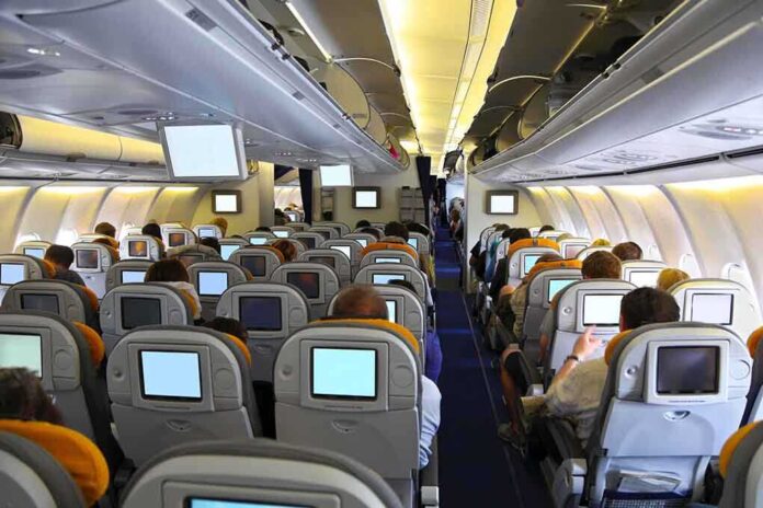 shutterstock_142431973.jpg Interior view of an airplane with passengers seated and using in-flight entertainment screens