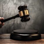 A hand holding a gavel above a wooden block