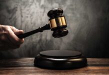 A hand holding a gavel above a wooden block