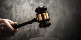 A hand holding a gavel above a wooden block