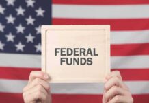 Person holding a sign that reads FEDERAL FUNDS in front of an American flag