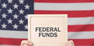 Person holding a sign that reads FEDERAL FUNDS in front of an American flag