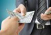 Two hands exchanging cash in a business setting
