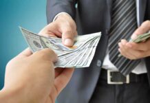 Two hands exchanging cash in a business setting