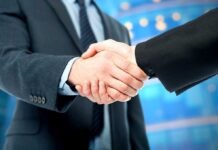 Newsom GOES Rogue–Strikes UK DEAL Two business professionals shaking hands in a corporate setting