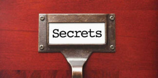 Metal label holder saying Secrets on wood background