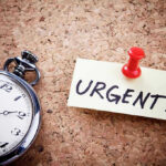 Pocket watch and urgent note pinned on corkboard