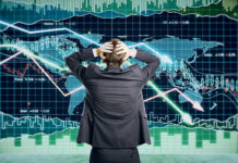 Person in front of falling stock market graph.