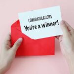 Hands holding a congratulations card and a red envelope