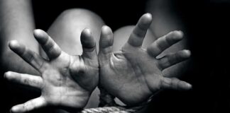 Two hands reaching out, bound by rope in a black and white image