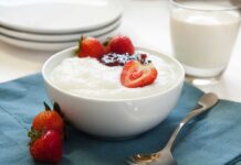 A bowl of creamy dessert topped with fresh strawberries and a drizzle of jam