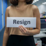 Person holding a sign that says resign