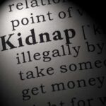 Close-up of a dictionary page showing the definition of the word 'kidnap'