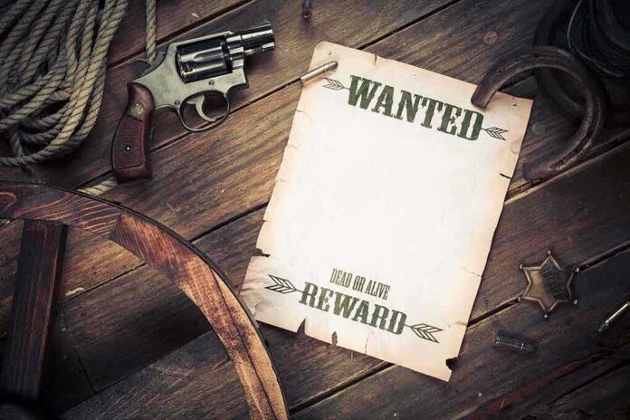 A vintage wanted poster alongside a revolver and rope on a wooden table