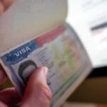 A hand holding a passport open to a visa page
