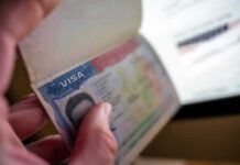 A hand holding a passport open to a visa page