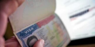A hand holding a passport open to a visa page