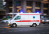 Nun Attack in Jerusalem—Shocking BRUTALITY Ambulance driving on urban street with lights flashing.