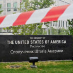 Kyiv Alert: Growing Threat Triggers Evacuation Pressure U.S. Embassy sign behind red-and-white caution tape.