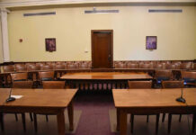 NDAA Adds Childcare, Intelligence Measures Empty courtroom with wooden tables, chairs, and a door.