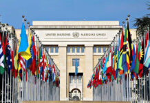 Vague Iran Deal Sparks Nuclear Jitters United Nations building with numerous national flags outside.