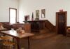 Interior of a historic courtroom with wooden furniture and an American flag