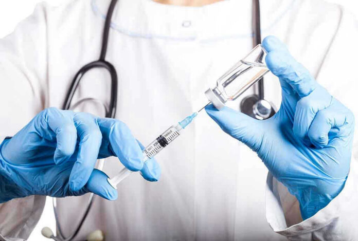 1310971853 Doctor filling syringe with vaccine from vial.