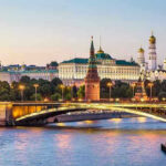 Anonymous Whale Makes Massive Bet on Putin’s Exit Illuminated bridge and Kremlin complex across river at twilight.