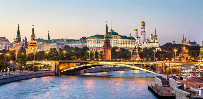 1419194690 Illuminated bridge and Kremlin complex across river at twilight.