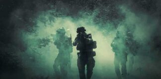 Soldiers move through dense smoke in a forest