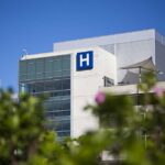 No Proof, Only Claims: The Mystery Condition Modern hospital building with a prominent H sign against a clear blue sky
