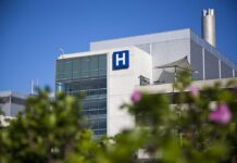 No Proof, Only Claims: The Mystery Condition Modern hospital building with a prominent H sign against a clear blue sky