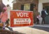 California’s Voter ID Measure Ignites New Political Battle Red voting sign with arrow near people entering a polling place