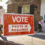California’s Voter ID Measure Ignites New Political Battle Red voting sign with arrow near people entering a polling place